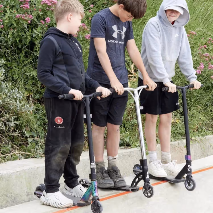 Three lads about to jump scooters down a ramp