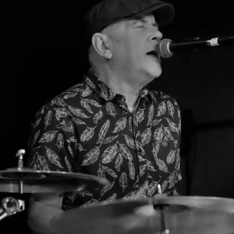 A man singing and playing drums