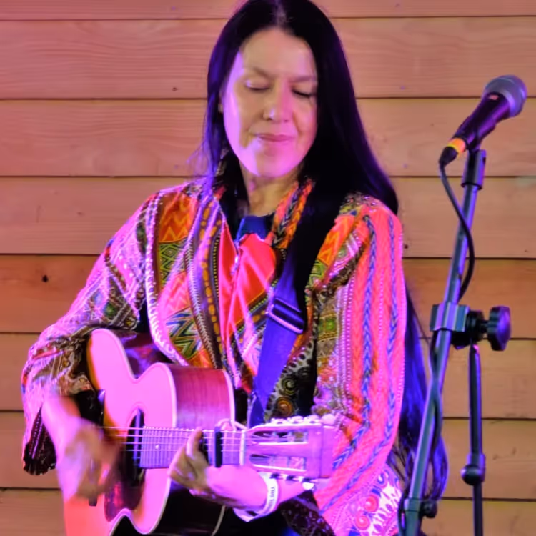 A woman with long hair playing acoustic guitar