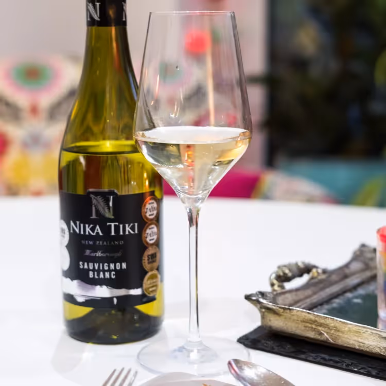 A glass of white wine next to its bottle