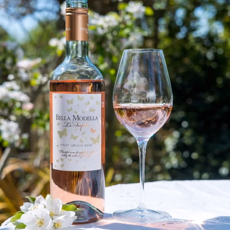 A glass of rose wine next to its bottle
