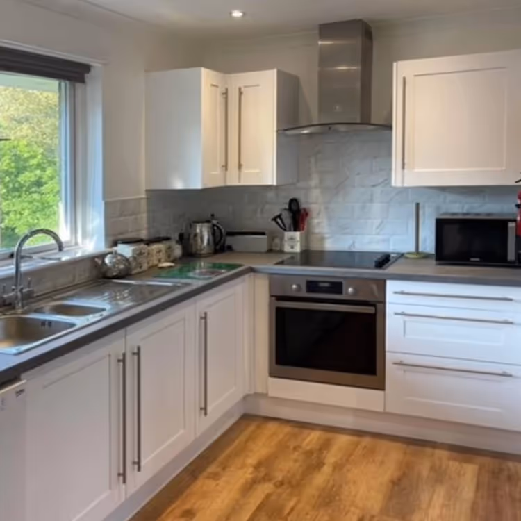 A modern white kitchen with wooden flooring