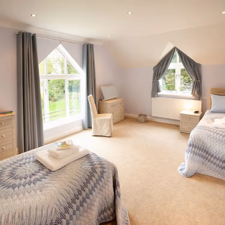 A cream and blue twin bedroom with vaulted ceiling