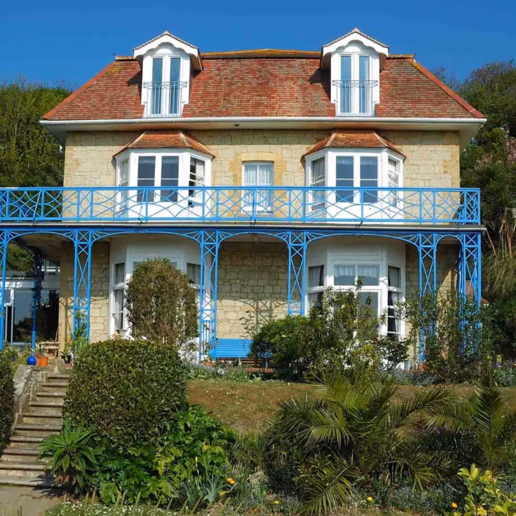 A Victorian stone house with blue metal balcony