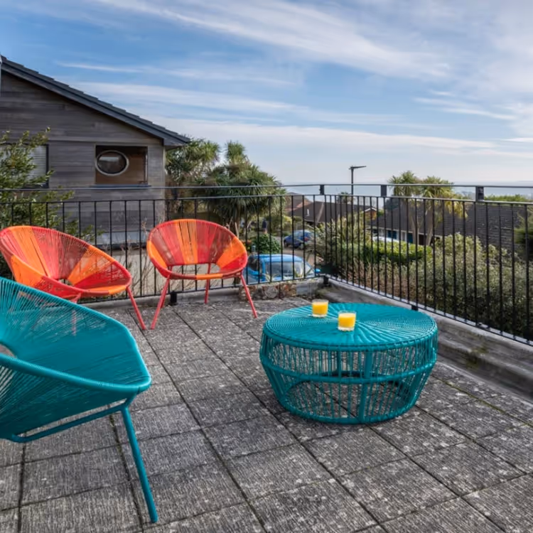A balcony with a sea view and 1970s style seating
