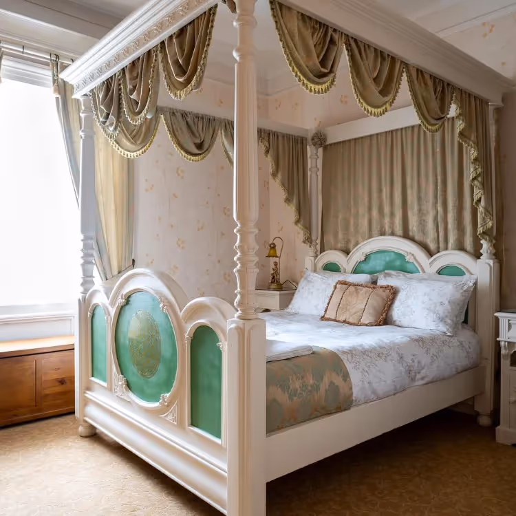 A white four poster bed in a romantic hotel bedroom