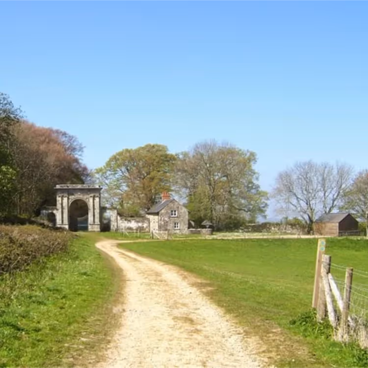 A path leading to a stone arch of a manor house