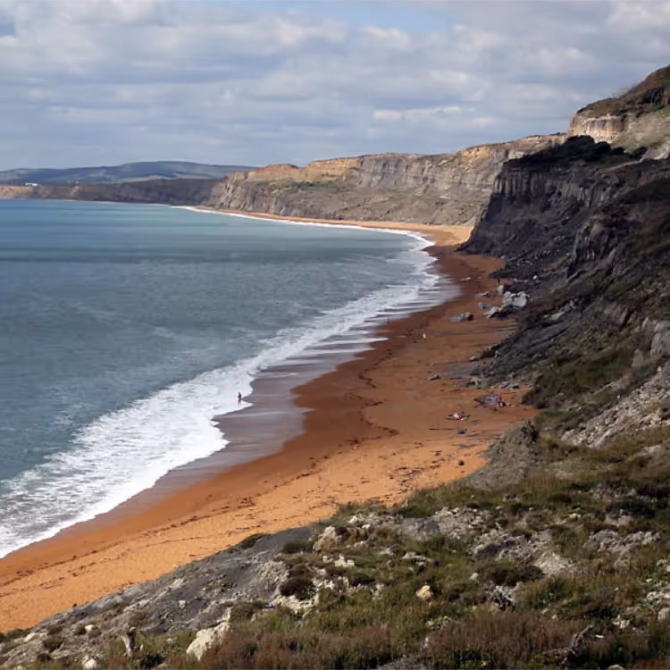 A sandy beach at the bottom of a steep cliff