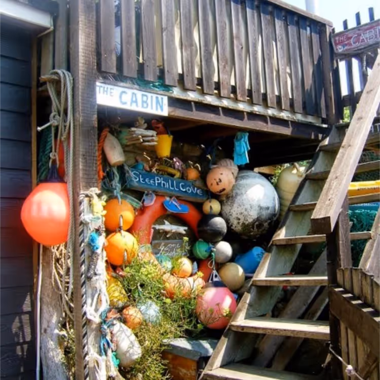 Wooden steps leading up to decking with fishing floats stored underneath