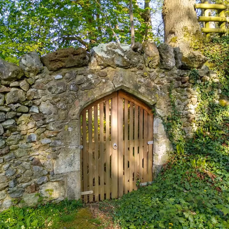 An arched wooden gate in an old stone wall