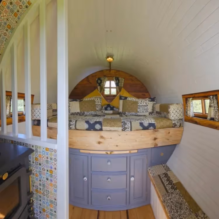 A bed inside a glamping shepherds hut