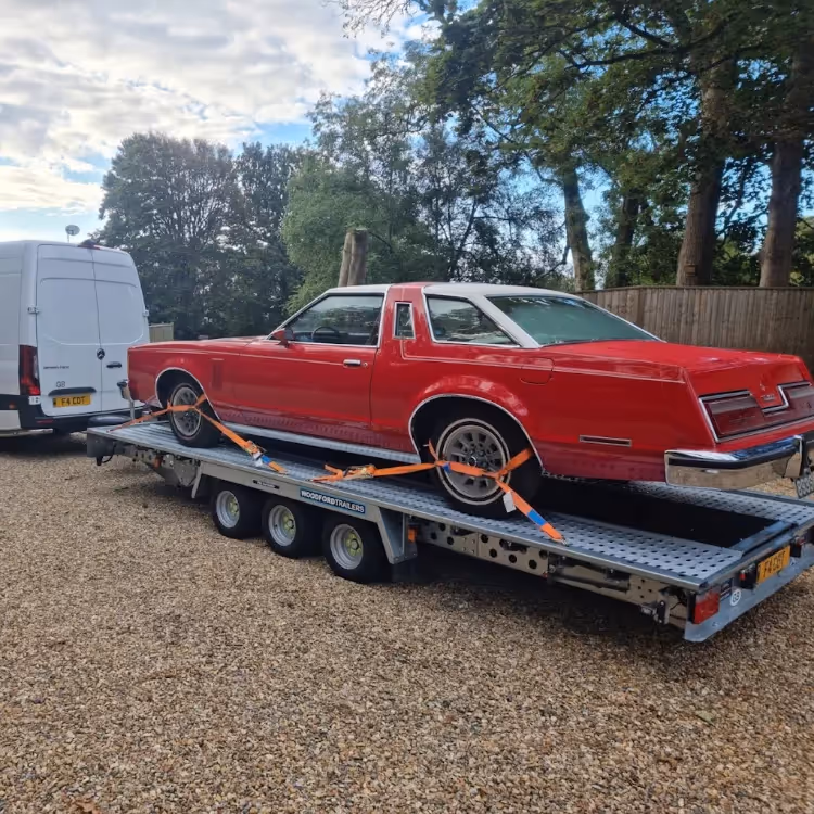 A classic American car being transported on a low loader