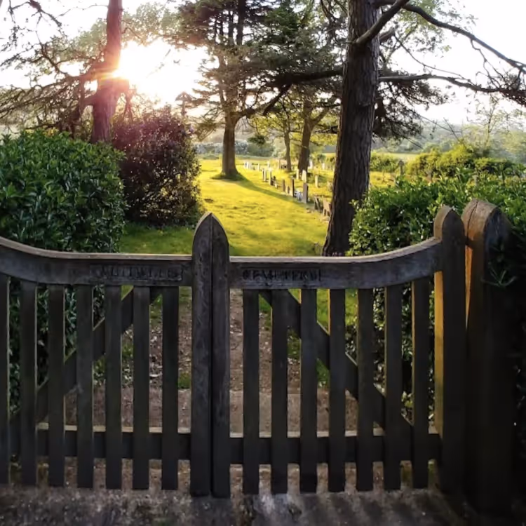 A pretty graveyard nearing sunset, with its wooden gates in the foreground