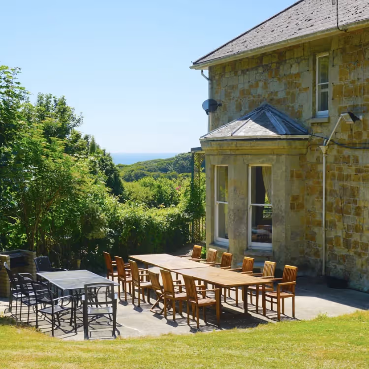 A large stone house with outside tables and chairs