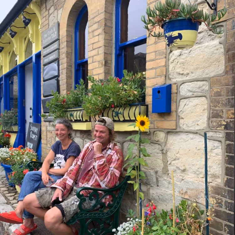 A man and lady sitting on a bench outside a pub