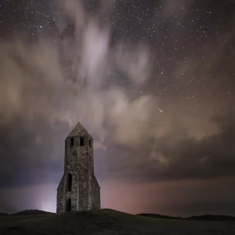 An old stone lighthouse under a star lit sky