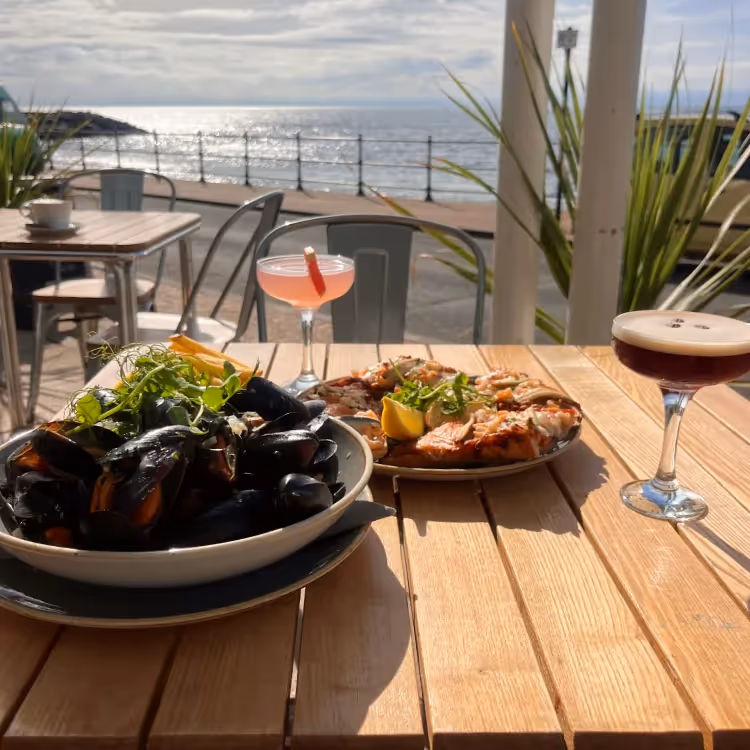 A bowl of fresh mussels on a table by the beach