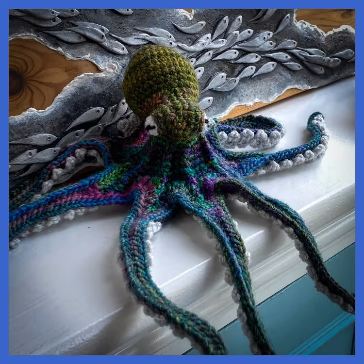 A hand crocheted octopus in green, teal and purple