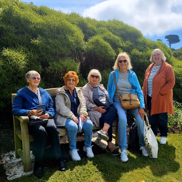 A group of ladies sitting on a wooden bench