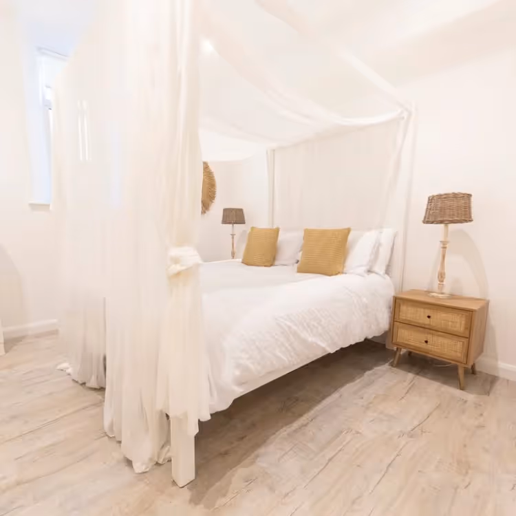 A romantic white bedroom with voile bed drapes