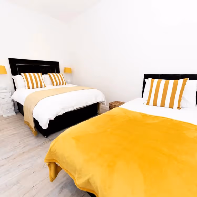 A yellow and black bedroom with two double beds