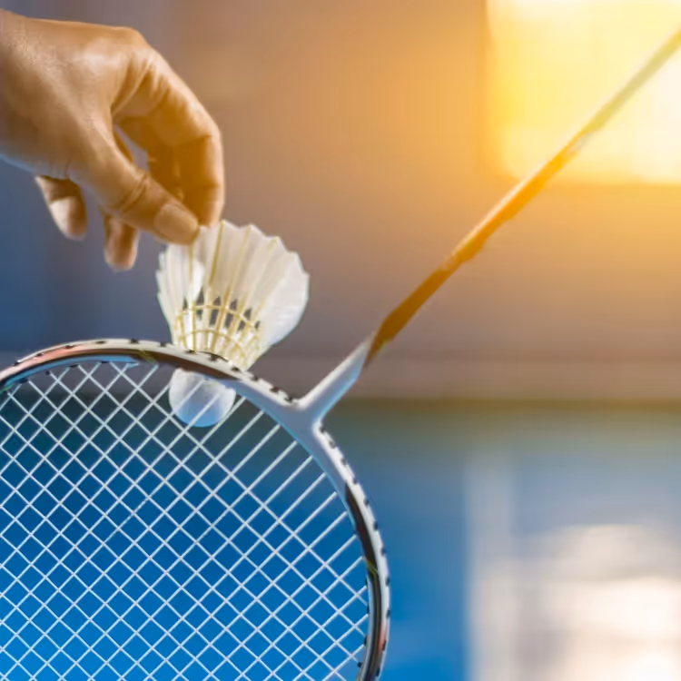 A shuttlecock held in front of a badminton racket