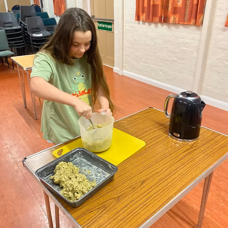 A girl making something in a kids cookery class