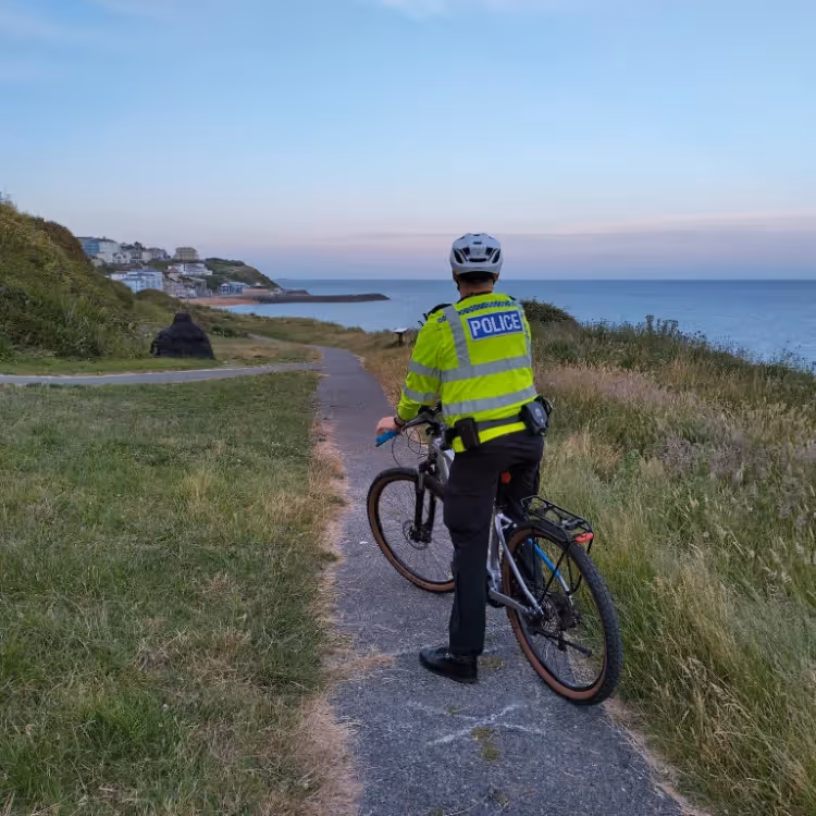 A policeman on bicycle patrol near a beach