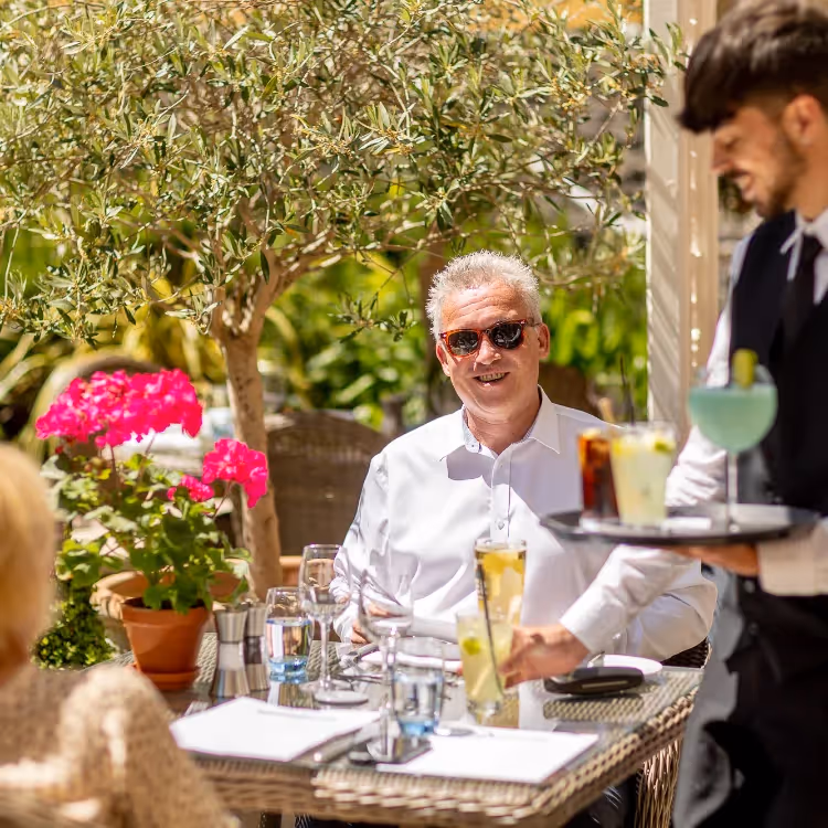 A waiter serving cocktail to a couple