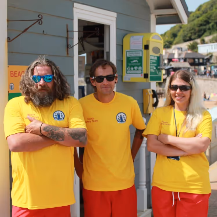Three members of a beach safety team dressed in red and yellow