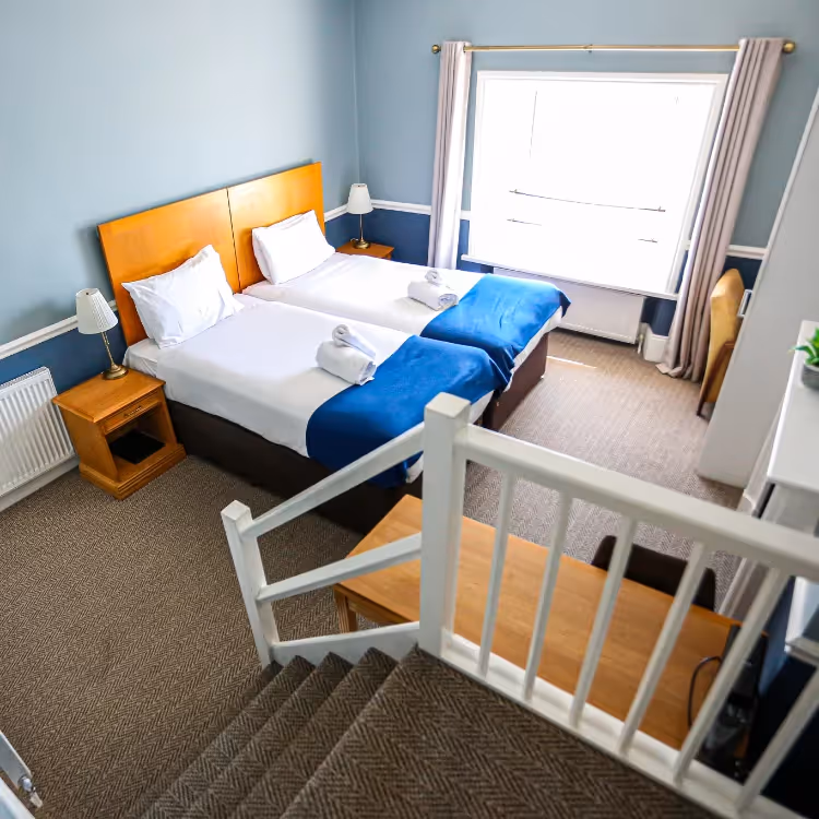 Steps leading down into a hotel room furnished in blue and white.