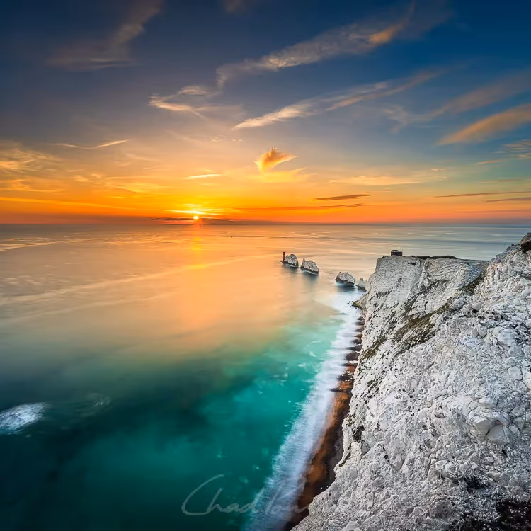 Looking down a rocky coastline to a sunset over the sea