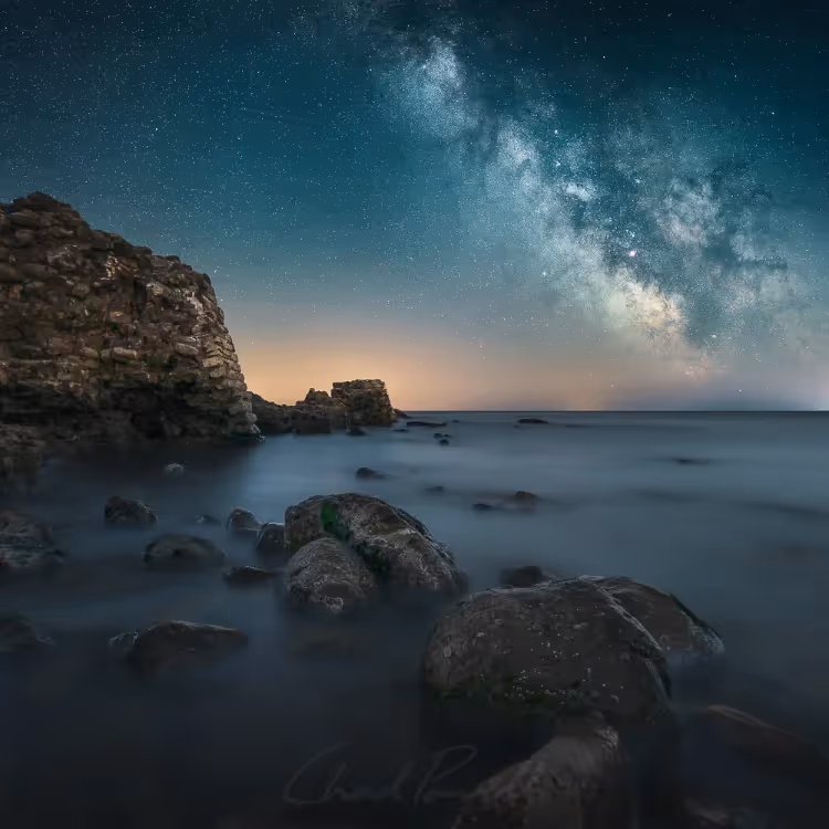 The Milky Way over a rocky cove