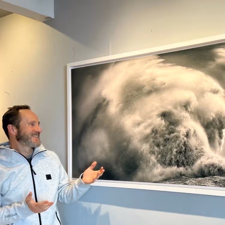A photographer stood by his framed photo of a stormy wave