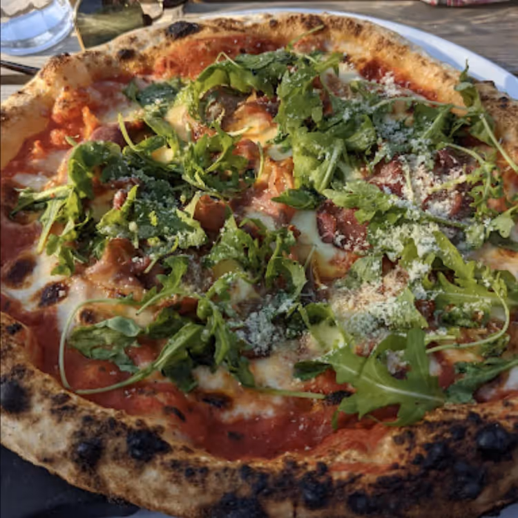A pizza tipped with rocket leaves
