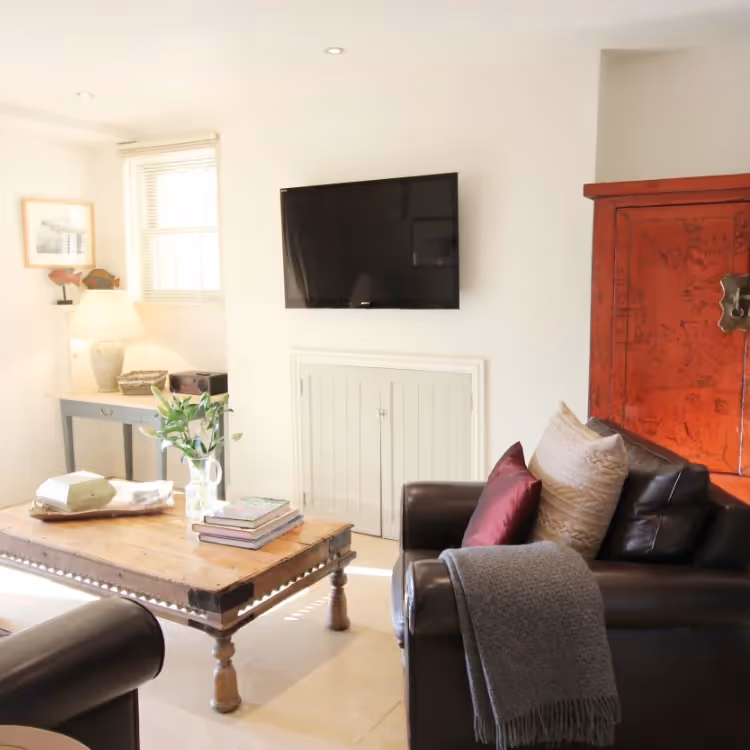 A living room with black sofas and a red chinese cabinet