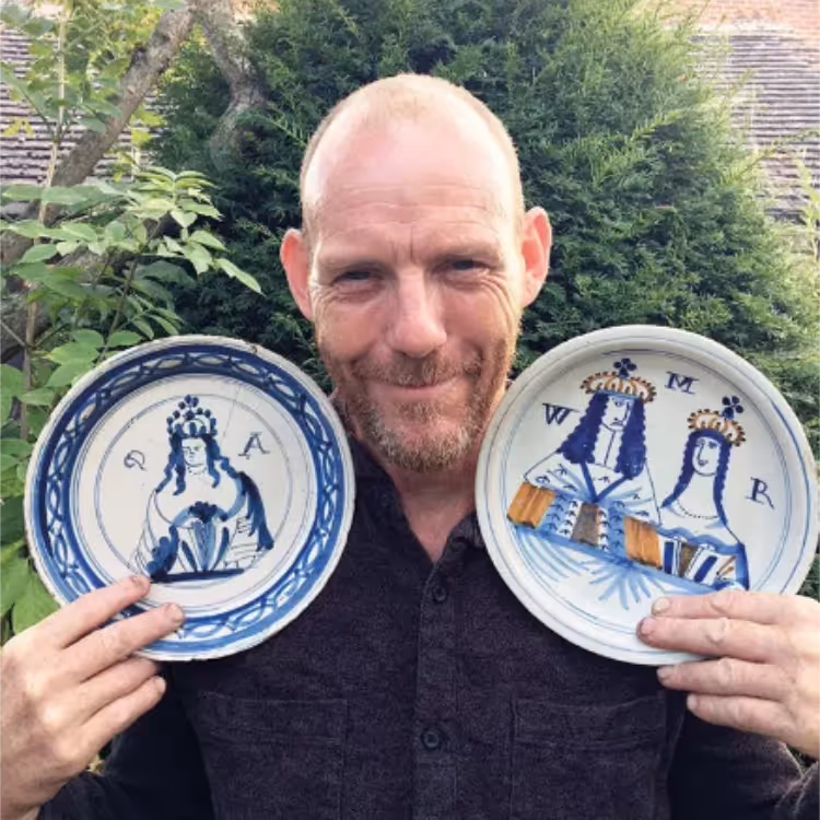 A man holding two Delftware ceramic plates
