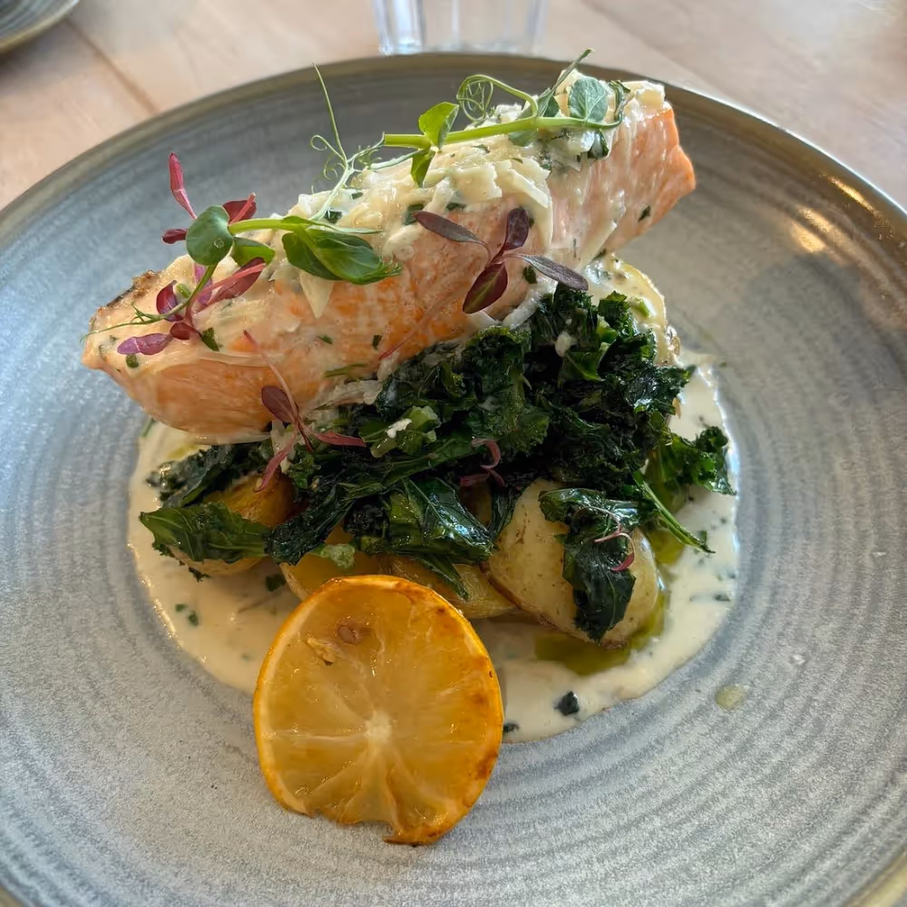 A dish of cooked salmon with spinach and buttered potatoes