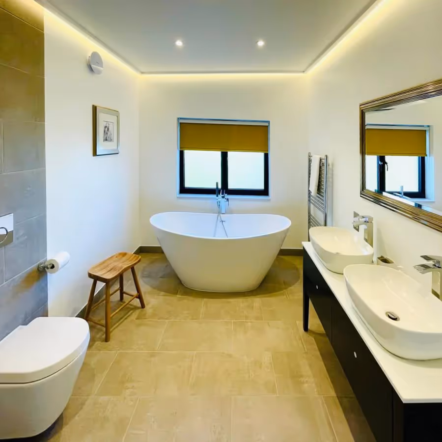 A large bathroom with freestanding bath and his & hers basins