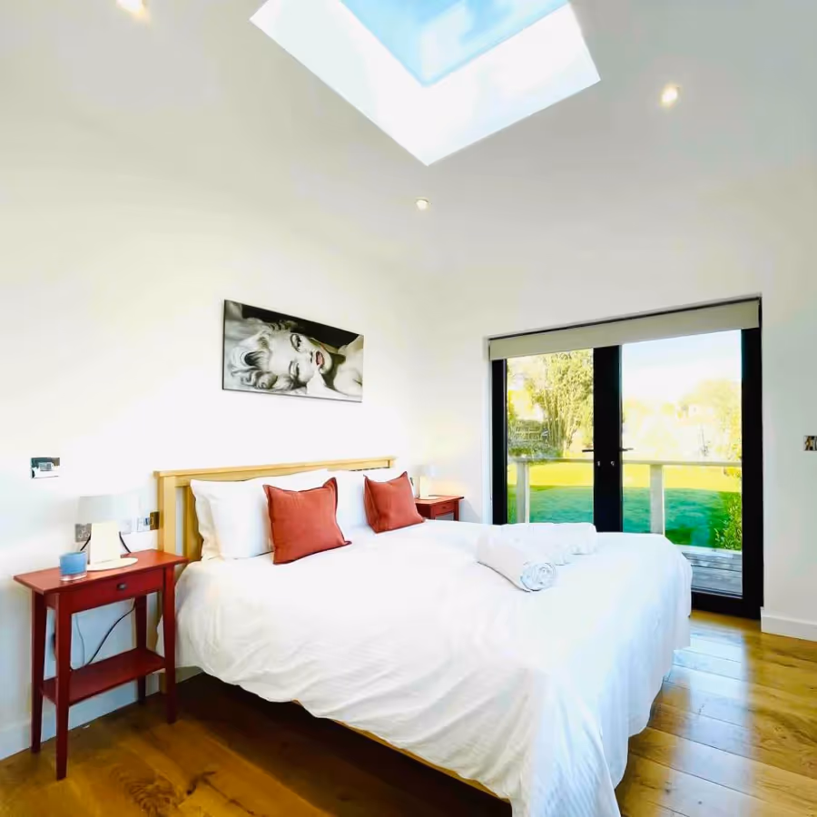 A large bedroom with doors leading out onto a garden