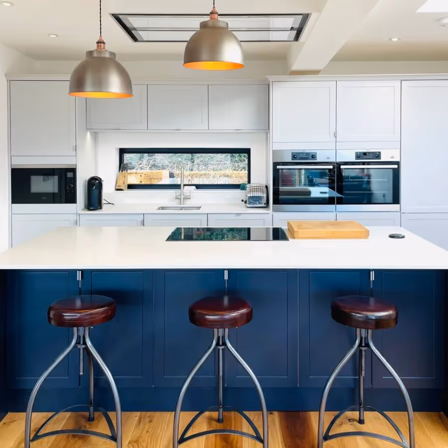 A dark blue kitchen with white worktops