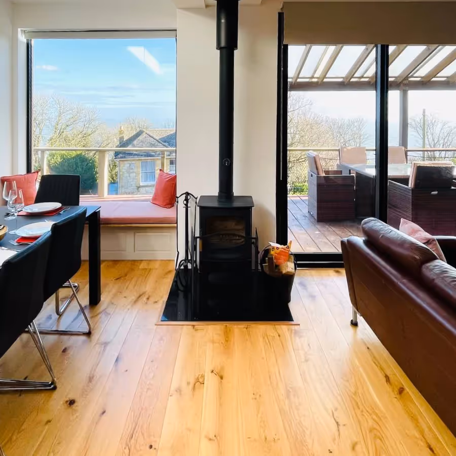 A living dining room with wood burning stove and a view to the sea beyond