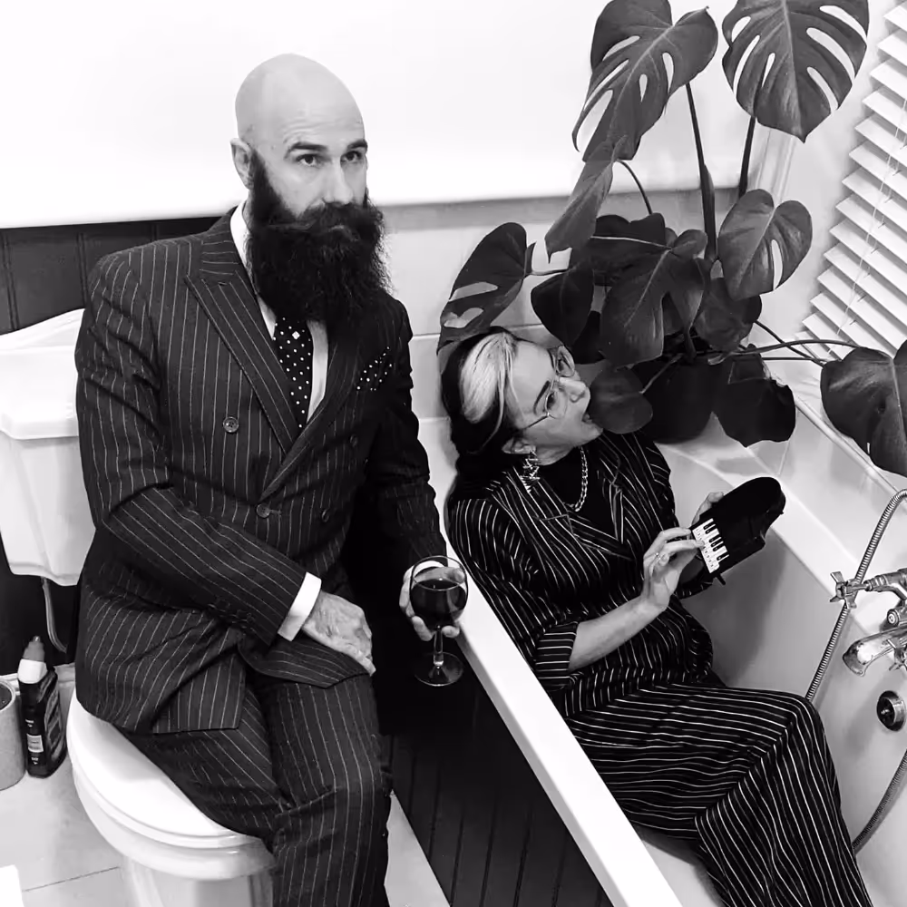 Black and white photo of a fully dressed couple in a bathroom