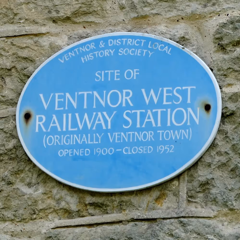 A blue plaque on the wall of an old railway station building