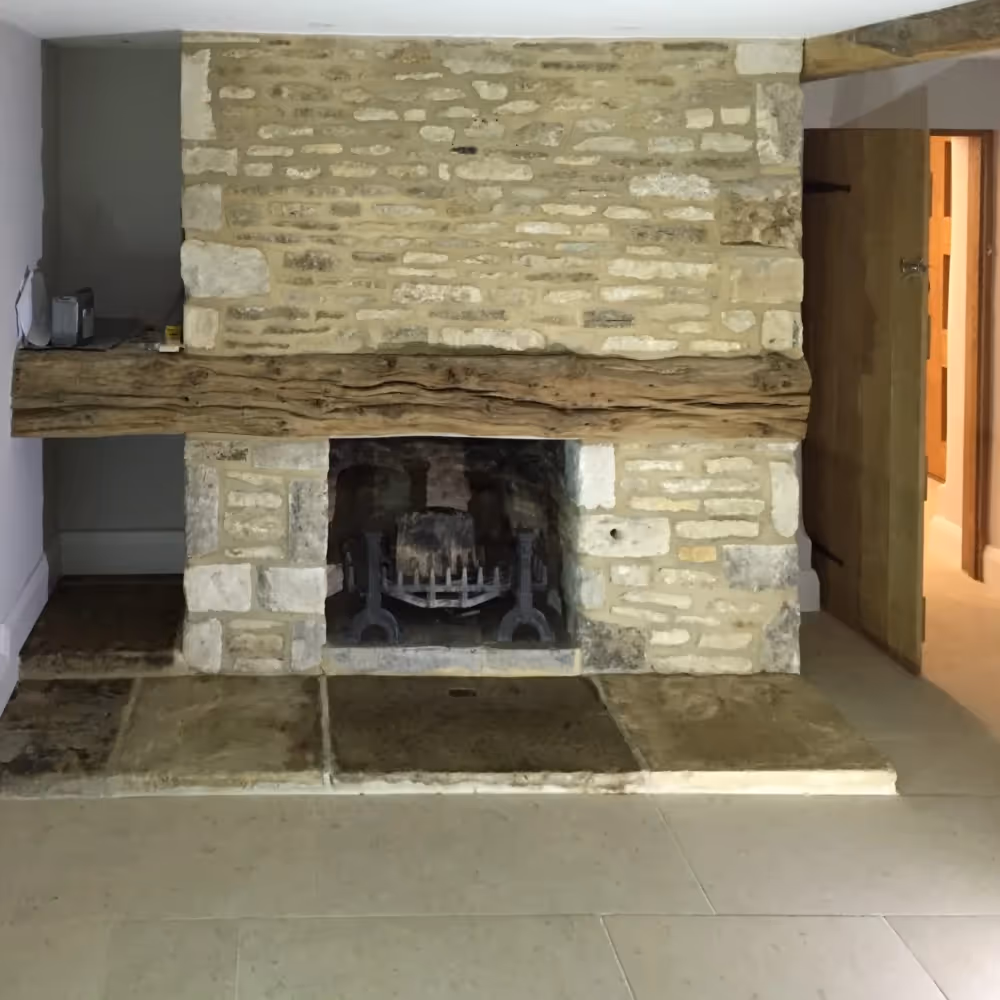 A country style stone fireplace with oak mantel