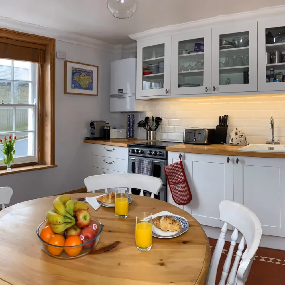 A white kitchen with a pine dining table