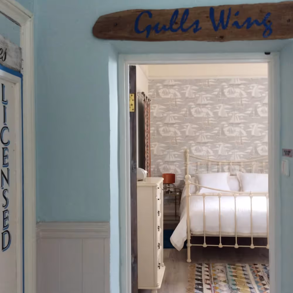An aqua hallway looking through a door into a pretty bedroom