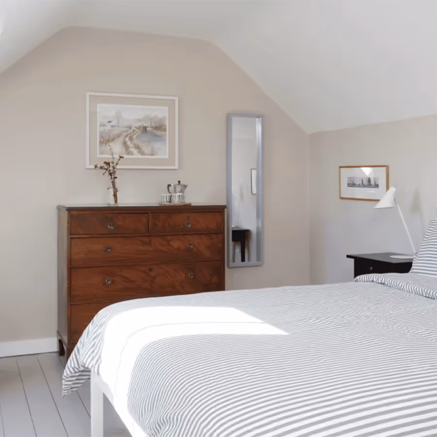 A neutral bedroom with a teak chest of drawers