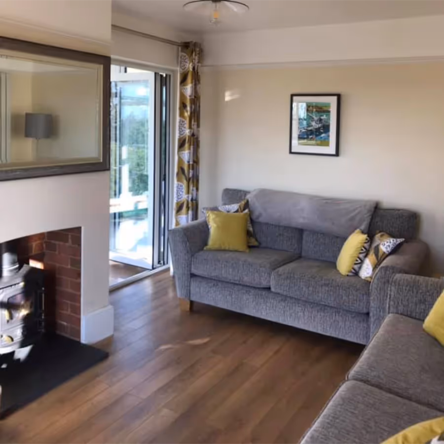 A living room with wooden floors and grey sofas
