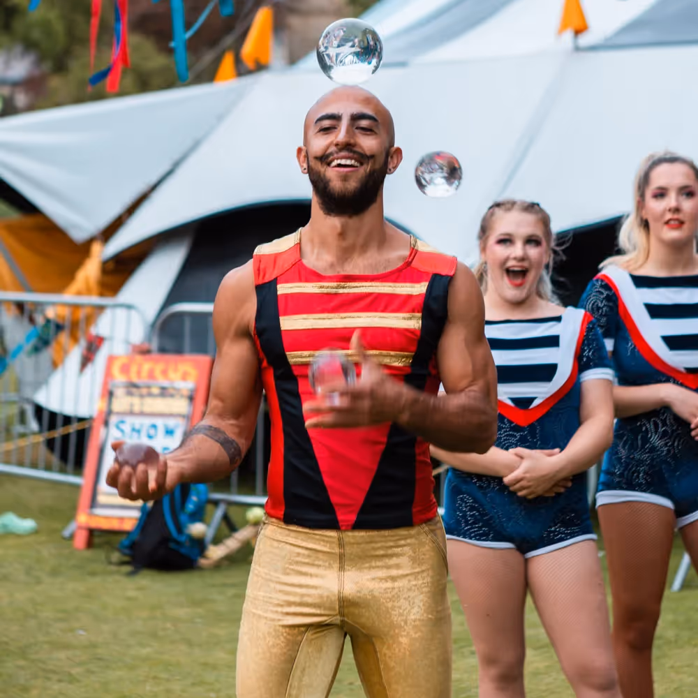 Three circus performers juggling glass spheres